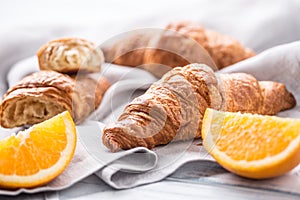 Fresh buttery croisants with sweet oranges on kitchen napkin