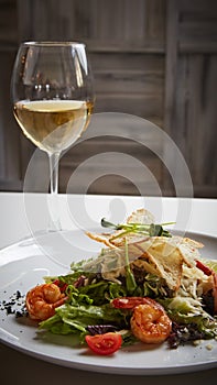 Fresh caesar salad on white bowl with parmesan cheese and shrimps.