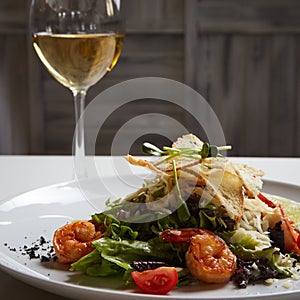 Fresh caesar salad on white bowl with parmesan cheese and shrimps.