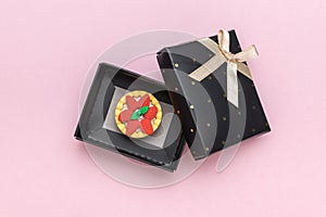 A fresh cake in a gift box on a pink background