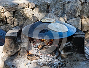 Fresh  cakes are fried on a large Bedouin roasting pan for cooking in camping conditions, heated on an open fire