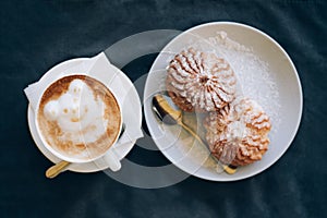 Fresh cappuccino art with plate with tasty cakes.