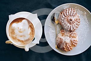 Fresh cappuccino art with plate with tasty cakes.
