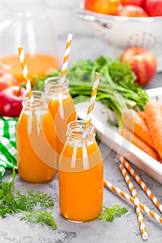 Fresh carrot and apple juice on white background. Carrot and apple juice in glass bottles on white table. Apple and carrot juice
