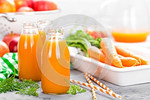 Fresh carrot and apple juice on white background. Carrot and apple juice in glass bottles on white table. Apple and carrot juice