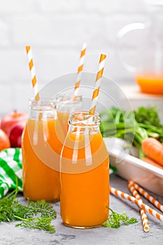 Fresh carrot and apple juice on white background. Carrot and apple juice in glass bottles on white table. Apple and carrot juice