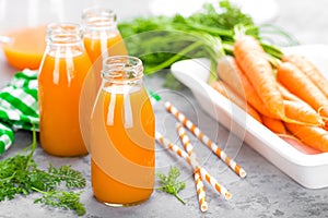 Fresh carrot and apple juice on white background. Carrot and apple juice in glass bottles on white table. Apple and carrot juice