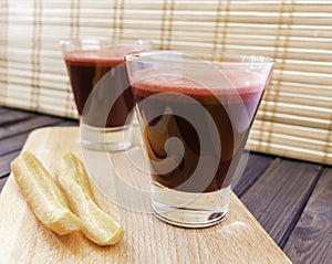 Fresh carrot and beetroot juice in glass decorated with carrot slices on wooden tray and bamboo background selective focus toned