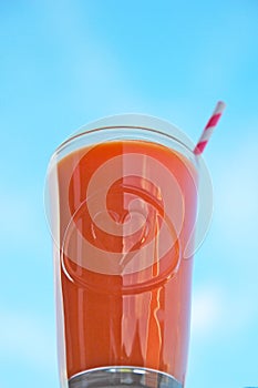 Fresh Carrot, orange and ginger juice against blue sky.