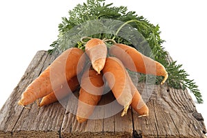 Fresh carrots with green leafy tops on rustic wooden table