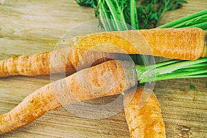 Fresh carrots with green tops close-up top view on wooden background