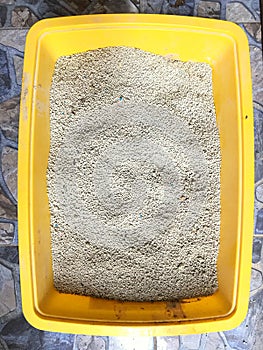 Fresh cat sand in a yellow litter box. Toilet cat