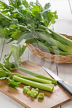 Fresh celery chopped on wooden cutting board.