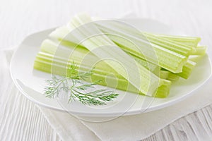 Fresh celery sticks with yogurt dip on white wooden background