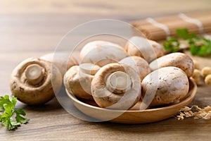 Fresh Champignon mushroom in bowl on wooden background