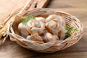 Fresh Champignon mushroom in natural basket on wooden background