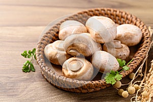 Fresh Champignon mushroom in natural basket on wooden background