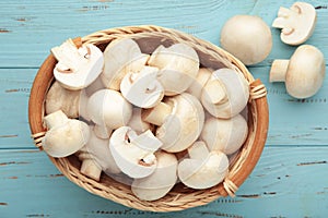 Fresh champignon mushrooms in basket on blue background