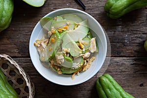 Fresh chayote fruits Sechium edulis stir fried with egg and garlic in bowl on wood background