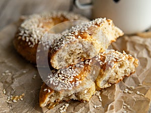 Fresh cheese donuts with sesame seeds on a wood background with metal white cup of coffee. Heathy food, diet, breakfast