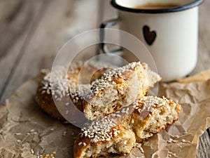 Fresh cheese donuts with sesame seeds on a wood background with metal white cup of coffee. Heathy food, diet, breakfast