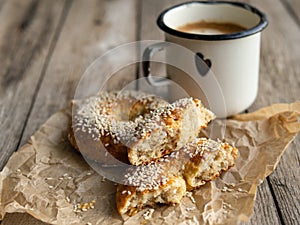 Fresh cheese donuts with sesame seeds on a wood background with metal white cup of coffee. Heathy food, diet, breakfast