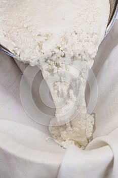 Fresh cheese making process, clotted cheese throw a cotton cloth, closeup photo