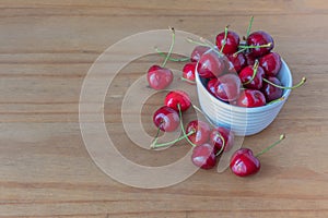 Fresh cherries in and around a white bowl