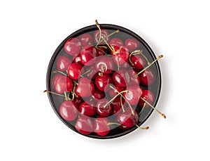 Fresh cherries in a black bowl on a white isolated  background. Top view and copy space