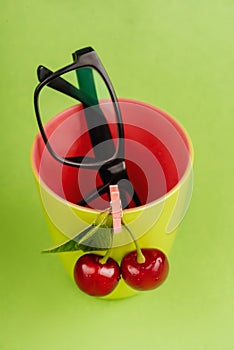 Cherries and glasses on green background