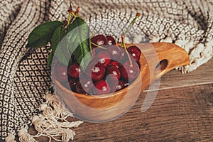 Fresh cherries with green leaves in wooden rustic bowl