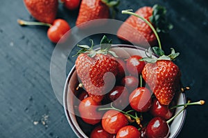 Fresh cherries and strawberries on the black wooden table, top v