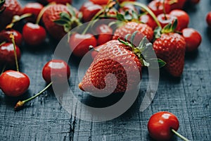 Fresh cherries and strawberries on the black wooden table, top v