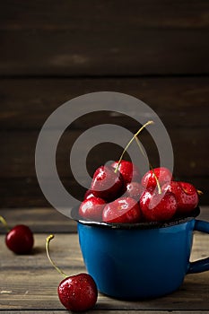 Fresh cherry with beautiful drops in a blue enamel mug