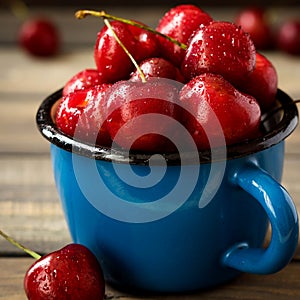 Fresh cherry with beautiful drops in a blue enamel mug