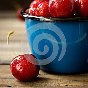 Fresh cherry with beautiful drops in a blue enamel mug