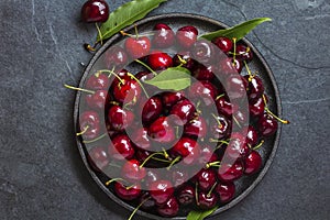 Fresh cherry on black plate, slate background. Top view