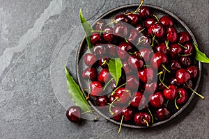 Fresh cherry on black plate. Top view copy space