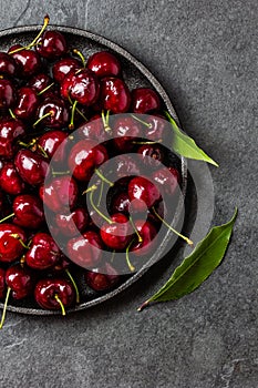 Fresh cherry on black plate. Top view copy space