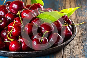 Fresh cherry on black plate, wooden background