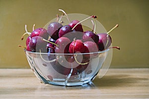 Fresh cherry glass bowl ready to serve. On a light-coloured wooden background, perfect for adding text