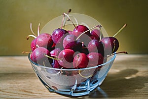 Fresh cherry glass bowl ready to serve. On a light-coloured wooden background, perfect for adding text