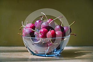 Fresh cherry glass bowl ready to serve. On a light-coloured wooden background, perfect for adding text