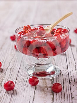 Fresh cherry jam in a vase with a wooden spoon.