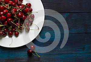 Fresh cherry on plate on wooden blue background. photo