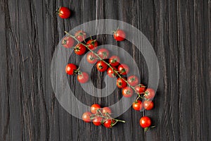 Fresh cherry tomato branches on wooden background top view