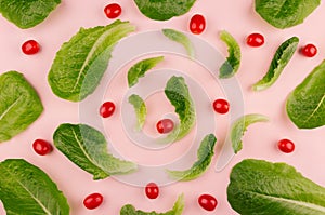 Fresh cherry tomato and leaves spinach on soft gentle pink background, pattern, cheerful modern spring food backdrop.