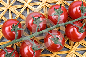 Fresh cherry tomatoes on a background of a straw mat.