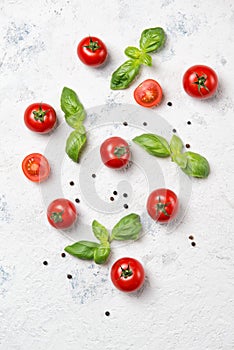 Fresh cherry tomatoes with basil leaves and black pepper on a stone table, vegetable pattern, top view