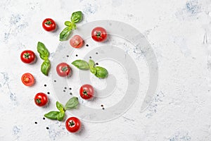 Fresh cherry tomatoes with basil leaves and black pepper on a stone table, vegetable pattern, top view with copy space